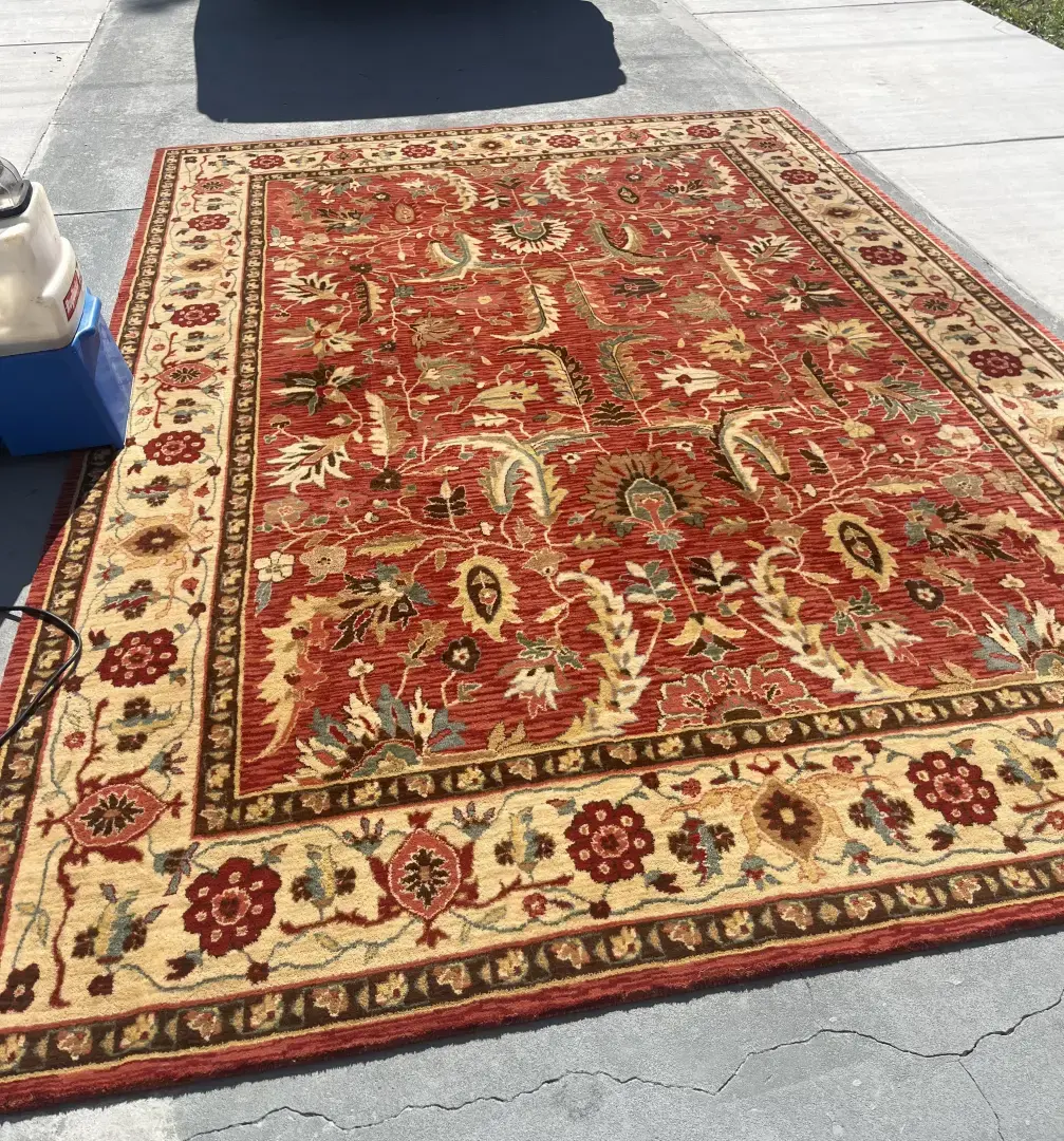 How Can Professional Rug Cleaning Restore the Beauty of a Decorative Area Rug? Large decorative floral area rug with earthy tones laid out on a driveway during professional rug cleaning in Dunedin FL