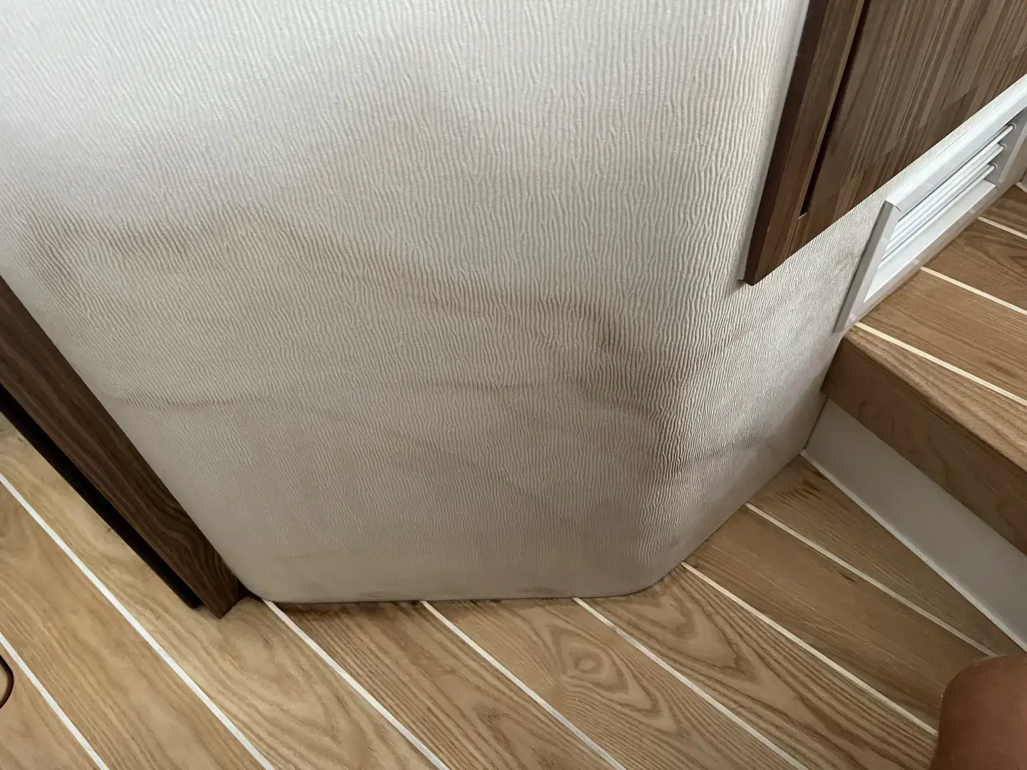 Contact Us Today Wall with visible water damage stains near wooden stairs inside a home interior.