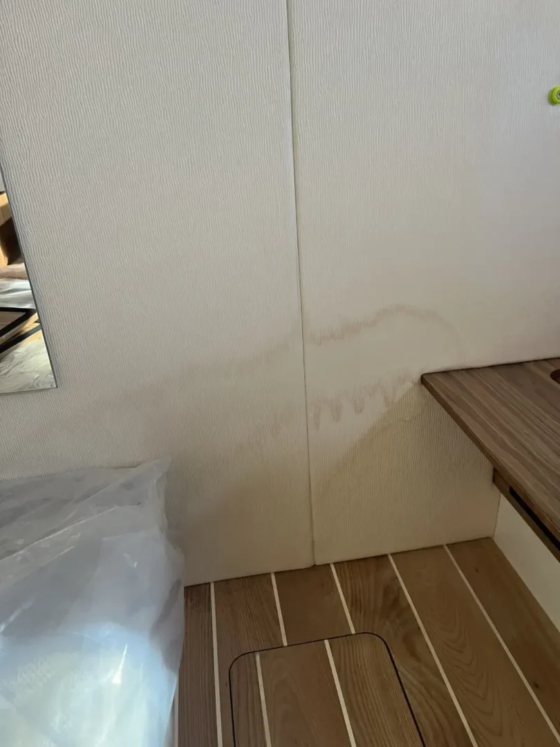 Contact Us Today Wall damage from water leakage next to wooden surface in a residential interior.