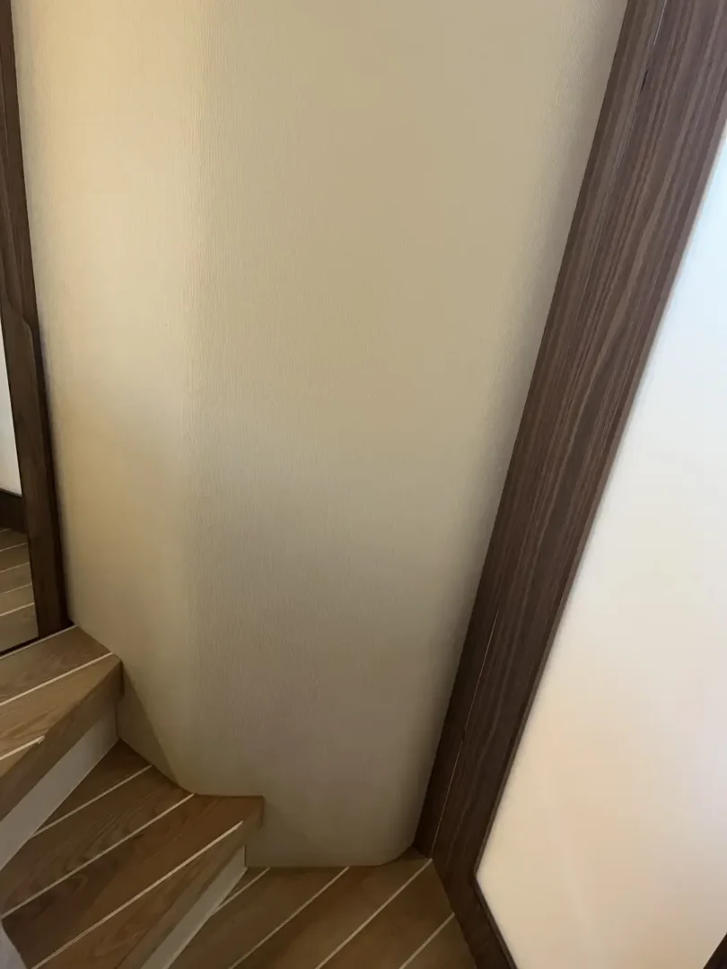 Contact Us Today Wall adjacent to wooden stairs showing distinct water damage stains in a home.