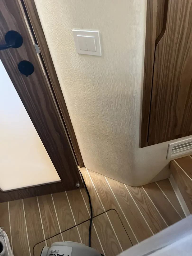 Contact Us Today Wall near a light switch and wooden staircase with water stain showing moisture damage.