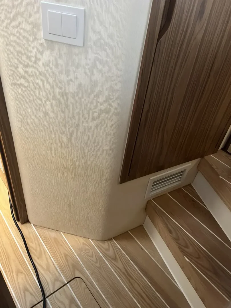 Contact Us Today Corner of interior space with wood flooring and stairs, featuring water stains on the wall.